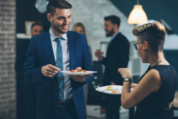 Business People Eating And Talking At Buffet In Business Lounge.