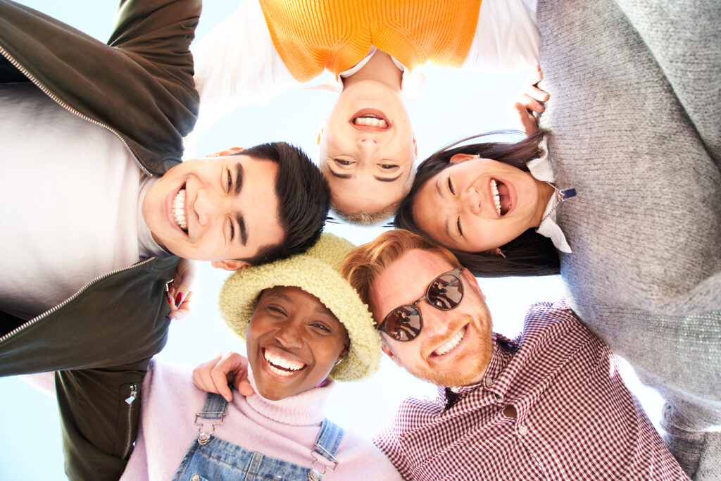 Multiracial And Diverse Group Of Friends Hugging In Circle And Looking Down At The Camera